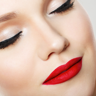 Close-up of a pair of lips coated in Karma Matte Red Lipstick, showcasing a bold, vivid red hue suitable for any makeup look.